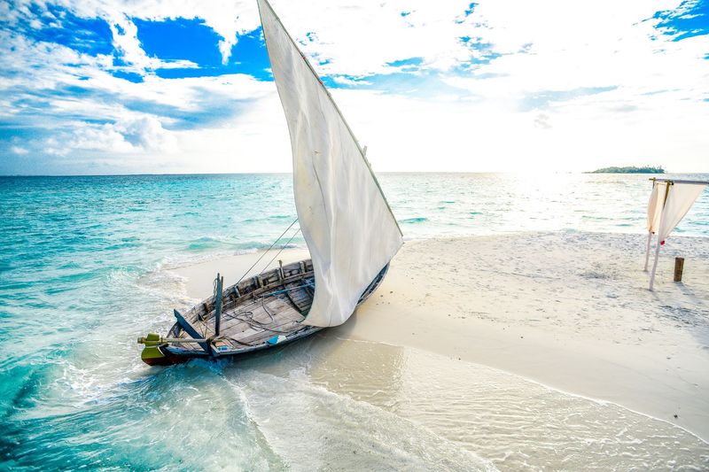 Traditional dhow resting on the white sand of a turquoise beach